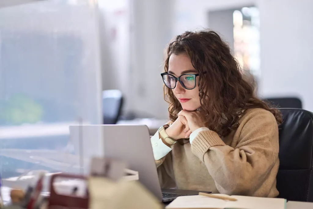 A woman is concentrating while working on her laptop